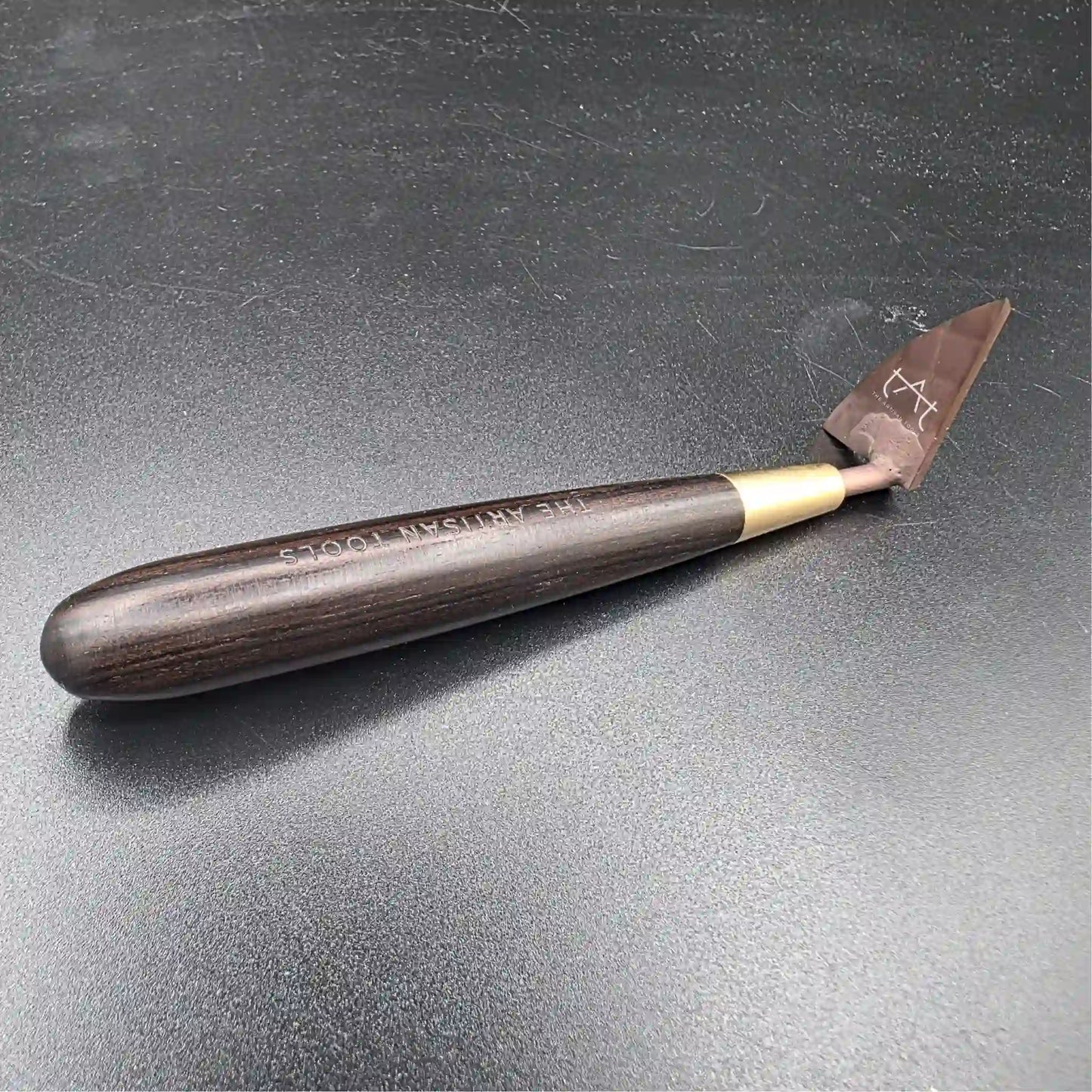 se ve la herramienta para recortar arcilla por la parte interior (mango de madera y cuchilla al fondo)