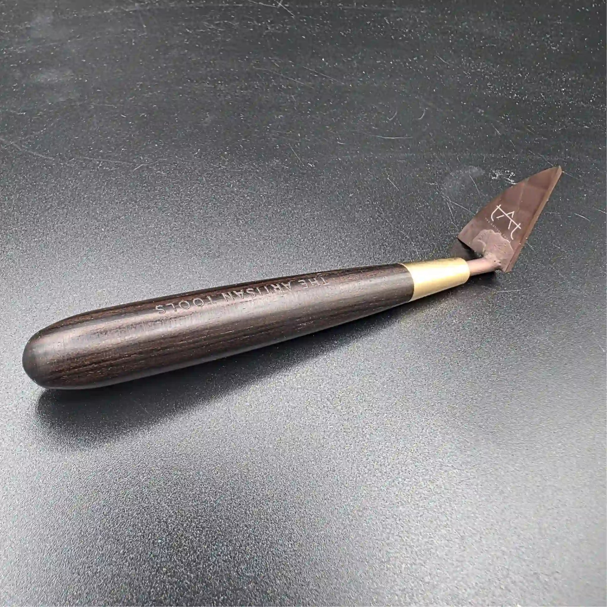 se ve la herramienta para recortar arcilla por la parte interior (mango de madera y cuchilla al fondo)